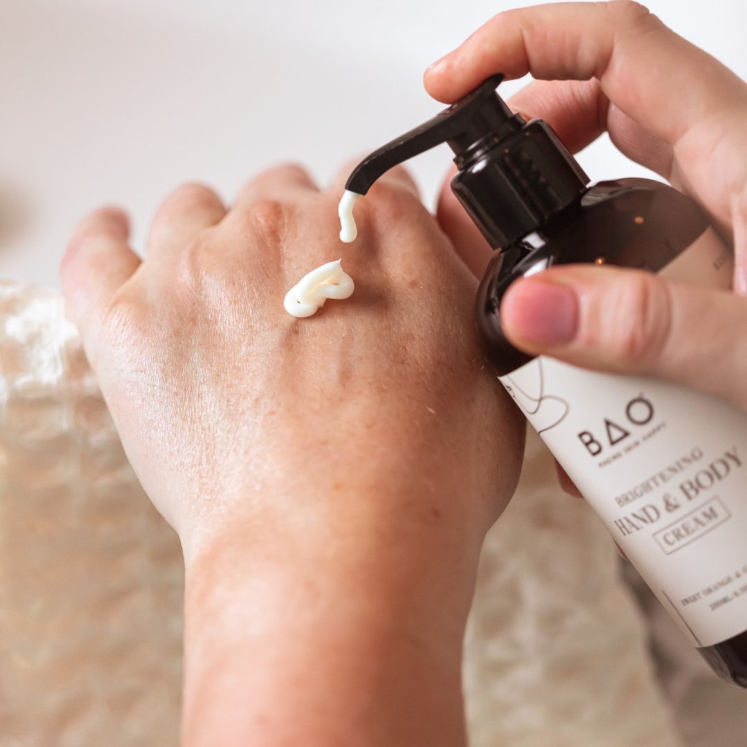 BAO Brightening Hand & Body Cream being dispensed from its pump onto the back of a hand