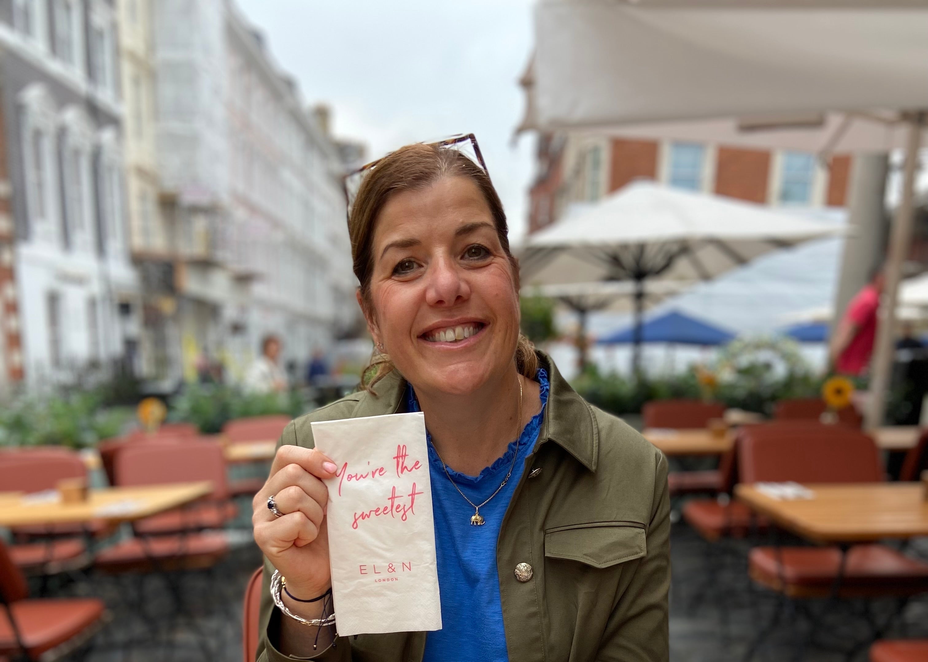 Woman holding a menu at an outdoor cafe with a sunflower on the table.