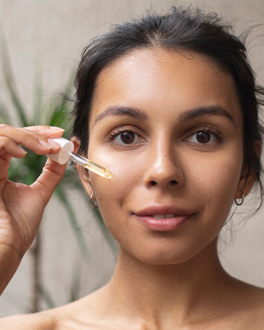 Woman using organic face oil on her skin to reduce oily skin and acne.
