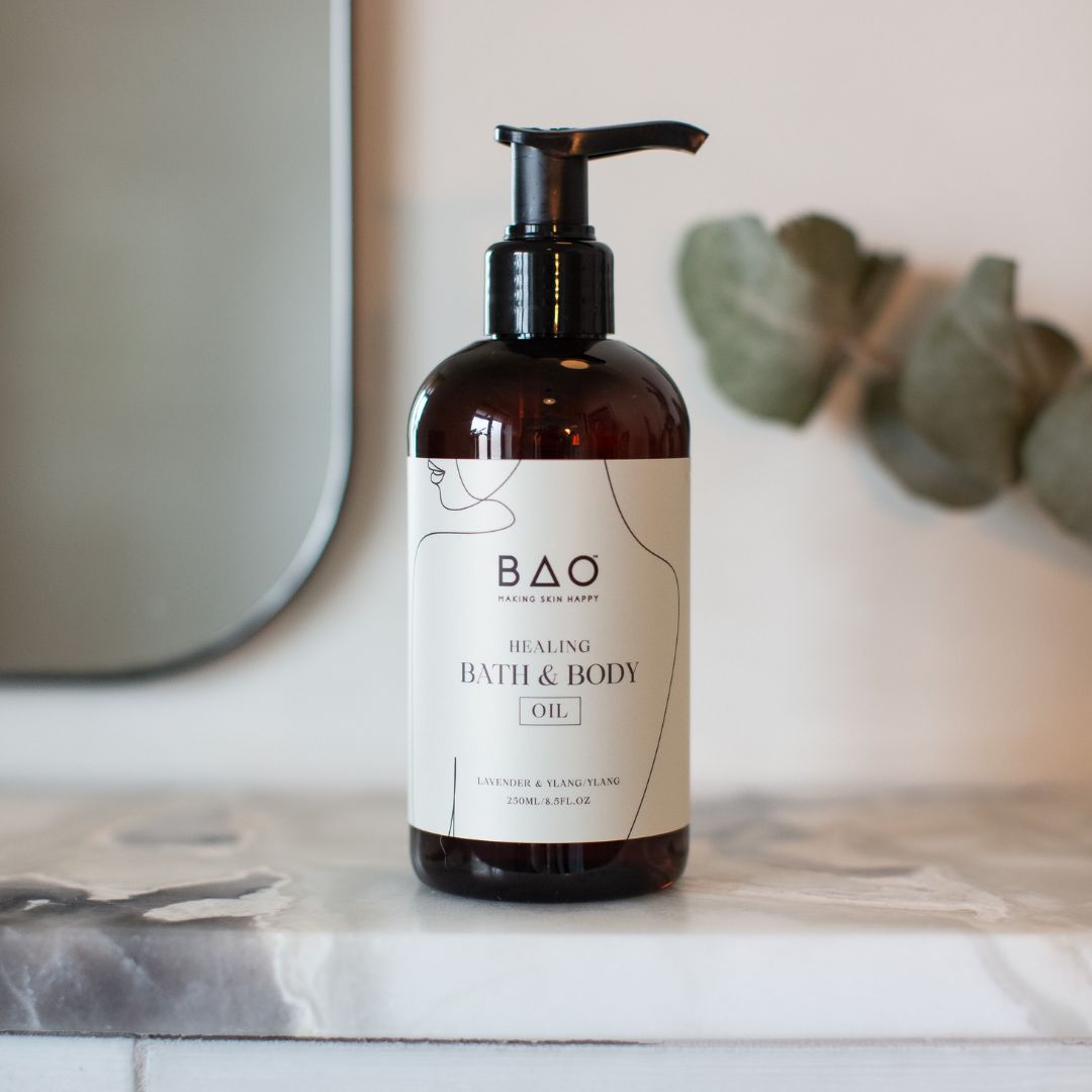 BAO Healing Bath & Body Oil bottle on a marble bathroom counter with eucalyptus leaves