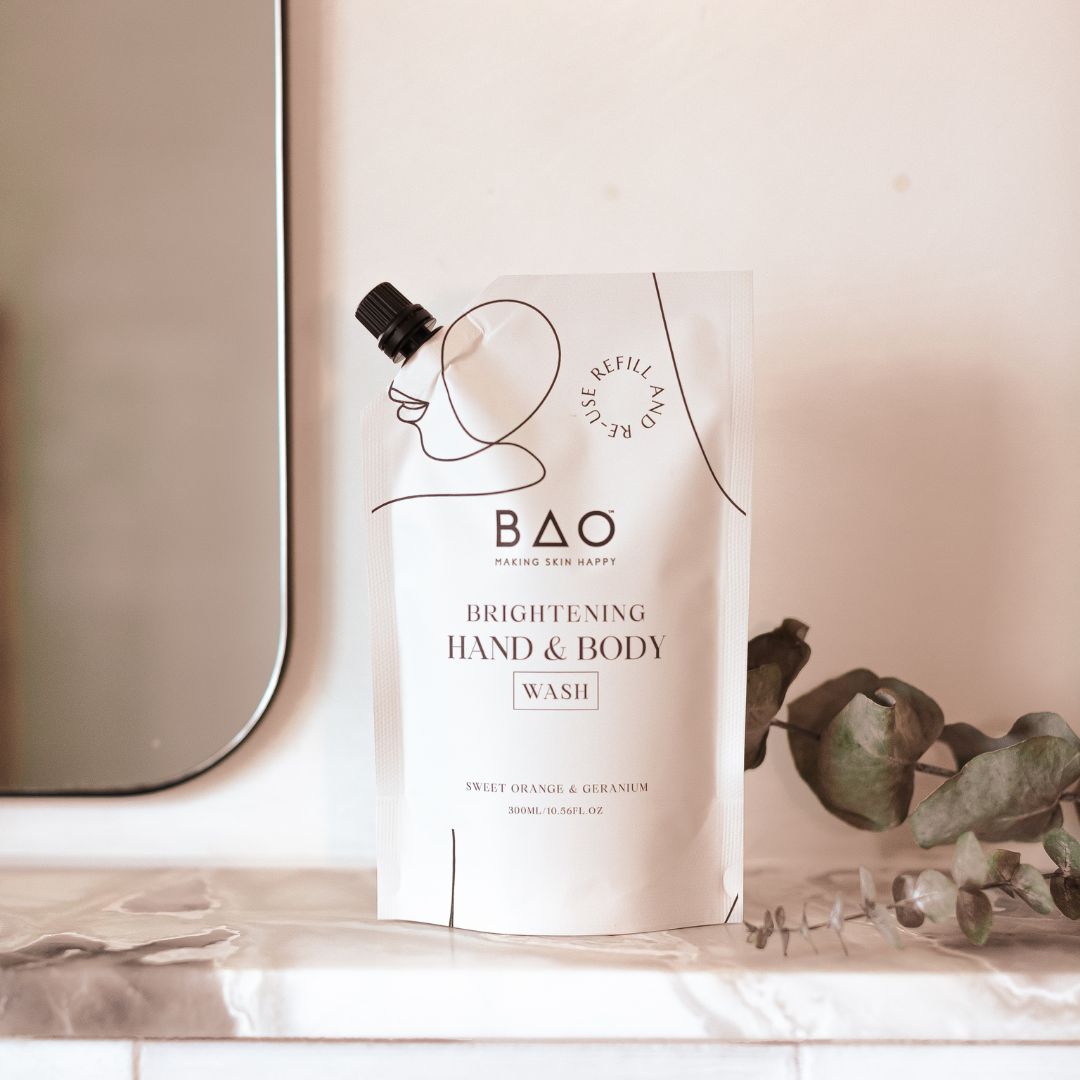 BAO Brightening Hand & Body Wash bottle and refill pouch on a marble shelf with eucalyptus