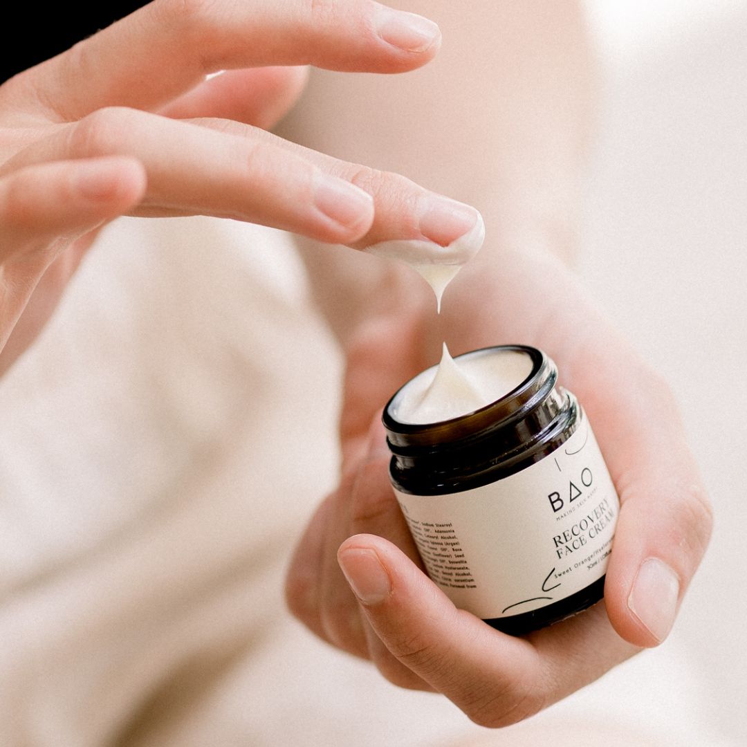 Fingers dipping into an open jar of BAO Recovery Face Cream to scoop out the product