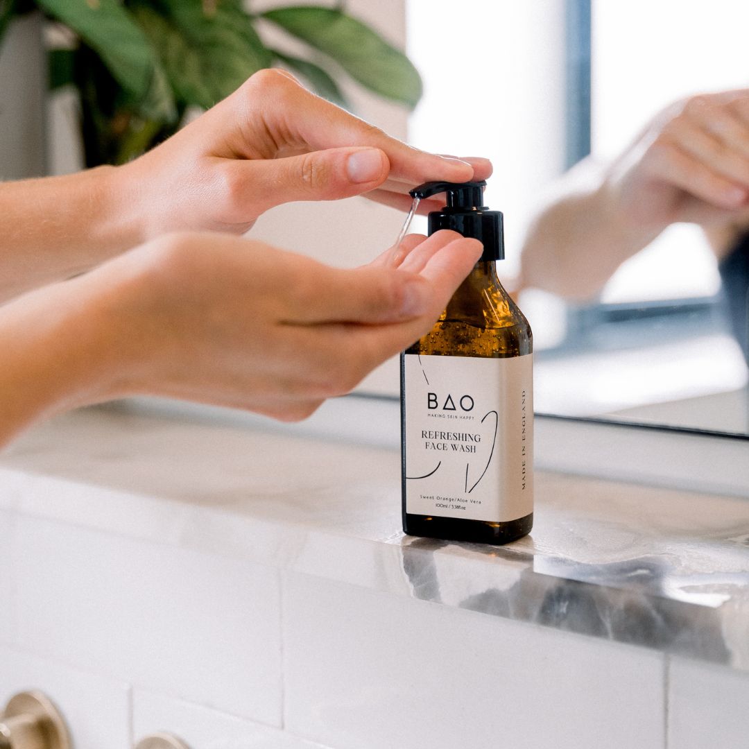 Hands pumping BAO Refreshing Face Wash from the bottle on a bathroom counter