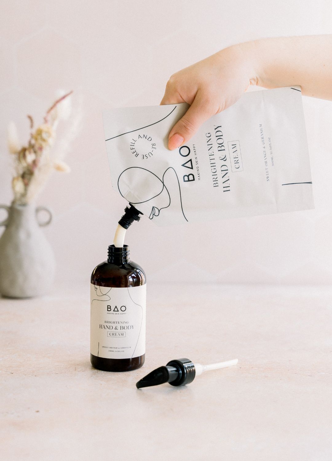 Pouring BAO Brightening Hand & Body Cream refill pouch into the pump bottle
