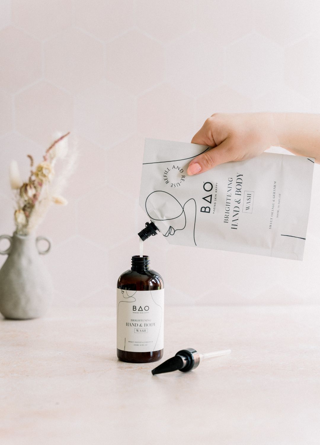 Pouring BAO Brightening Hand & Body Wash refill pouch into the pump bottle