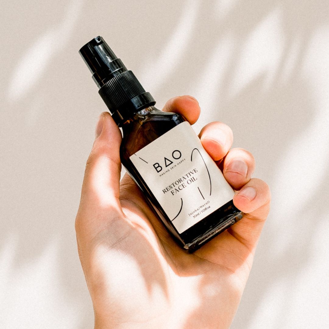 BAO Restorative Face Oil bottle held in a hand against a sunlit backdrop