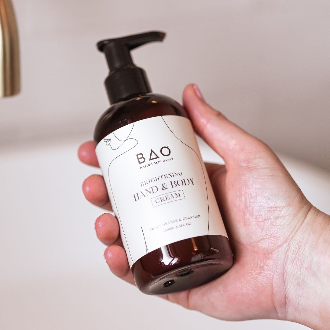 Hand holding the BAO Brightening Hand &amp; Body Cream bottle