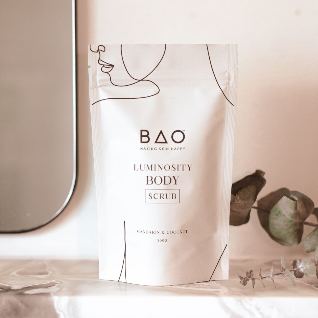 BAO Luminosity Body Scrub pouch displayed on a marble shelf with eucalyptus leaves