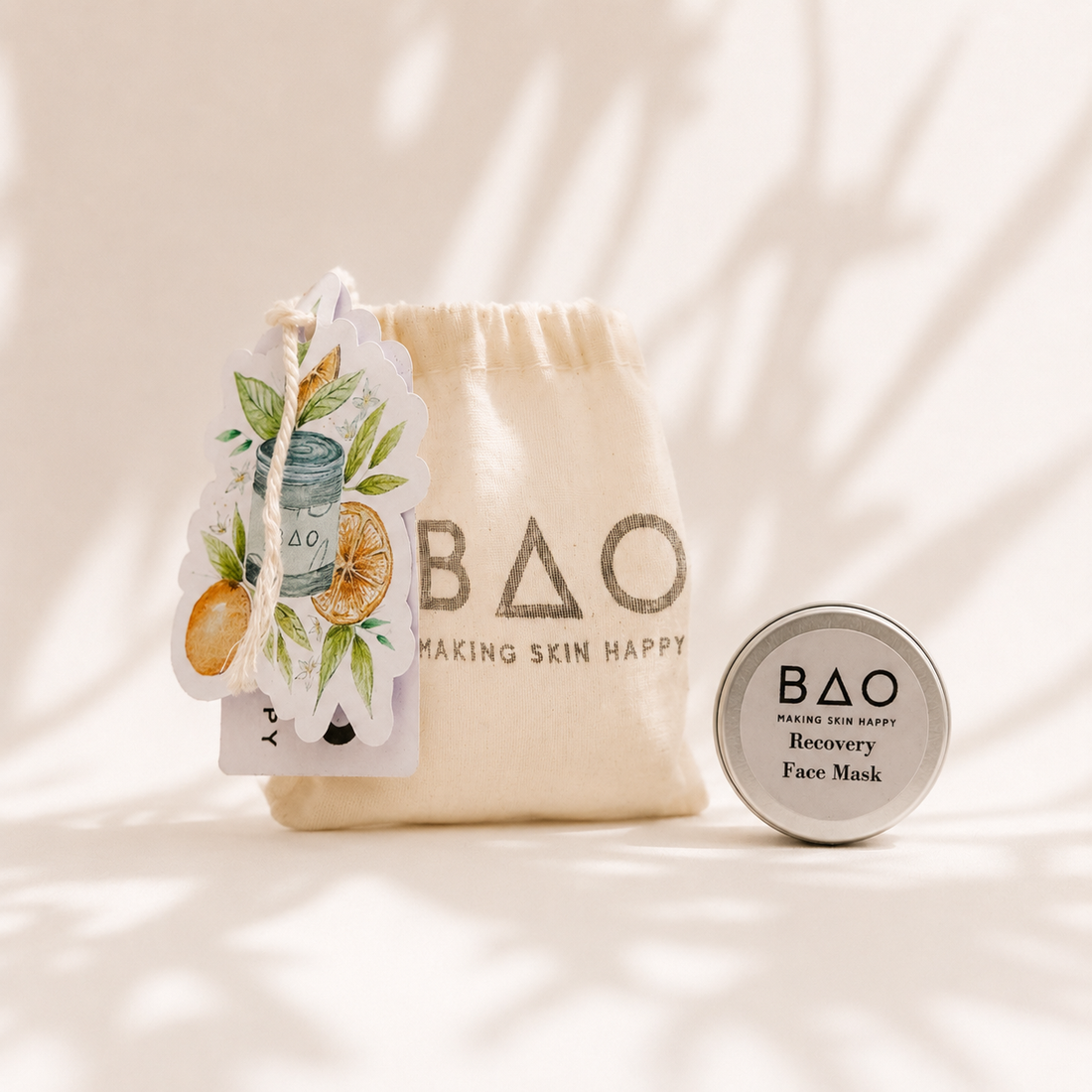 BAO Recovery Face Mask trial set displayed in a soft editorial skincare scene with a natural cotton BAO pouch, illustrated botanical tag and silver sample tin against a warm neutral background with delicate shadowing