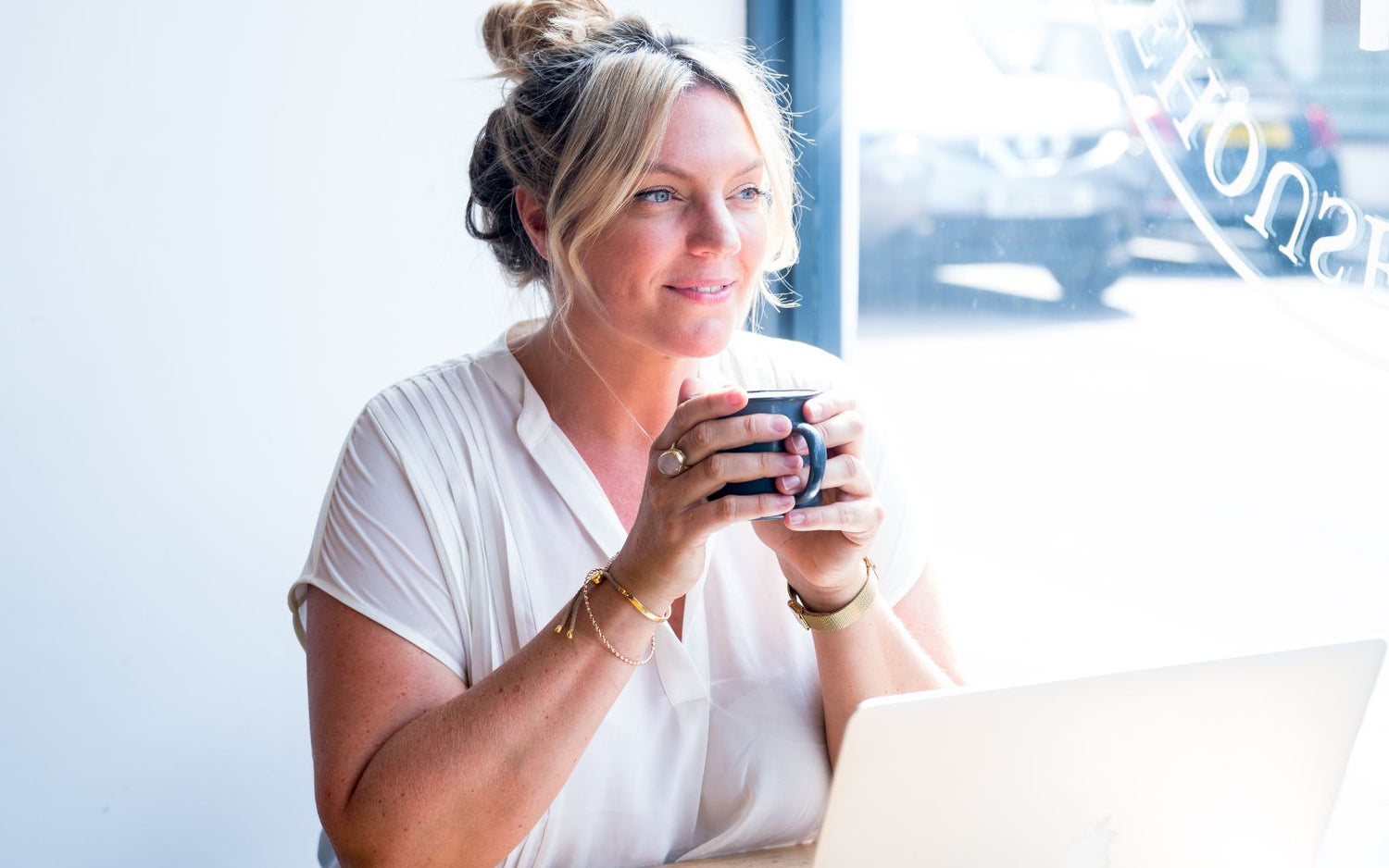 BAO Skincare founder Beth sitting in a cafe with a cup of organic green tea.
