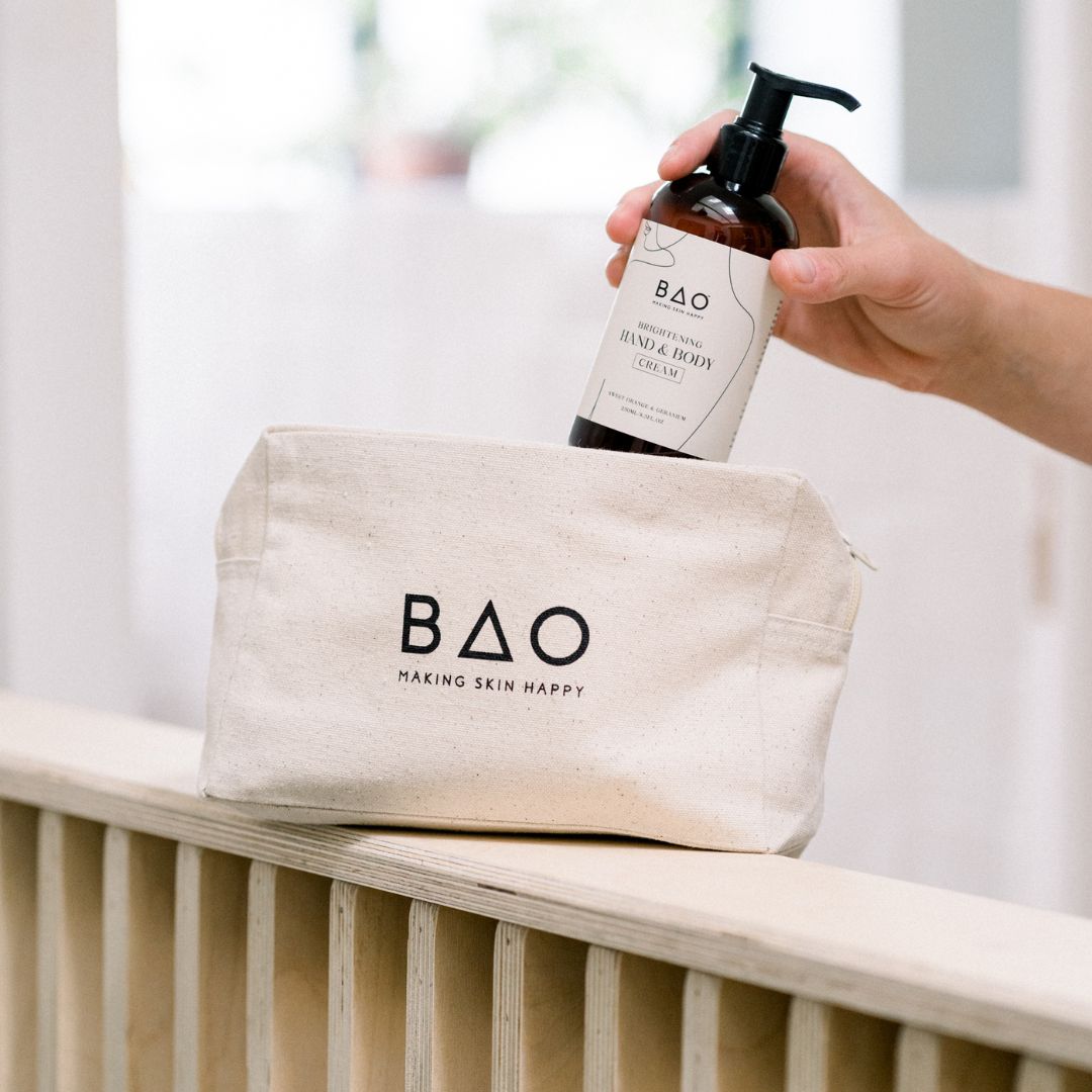 Hand placing BAO Brightening Hand &amp; Body Wash bottle behind the BAO canvas gift bag
