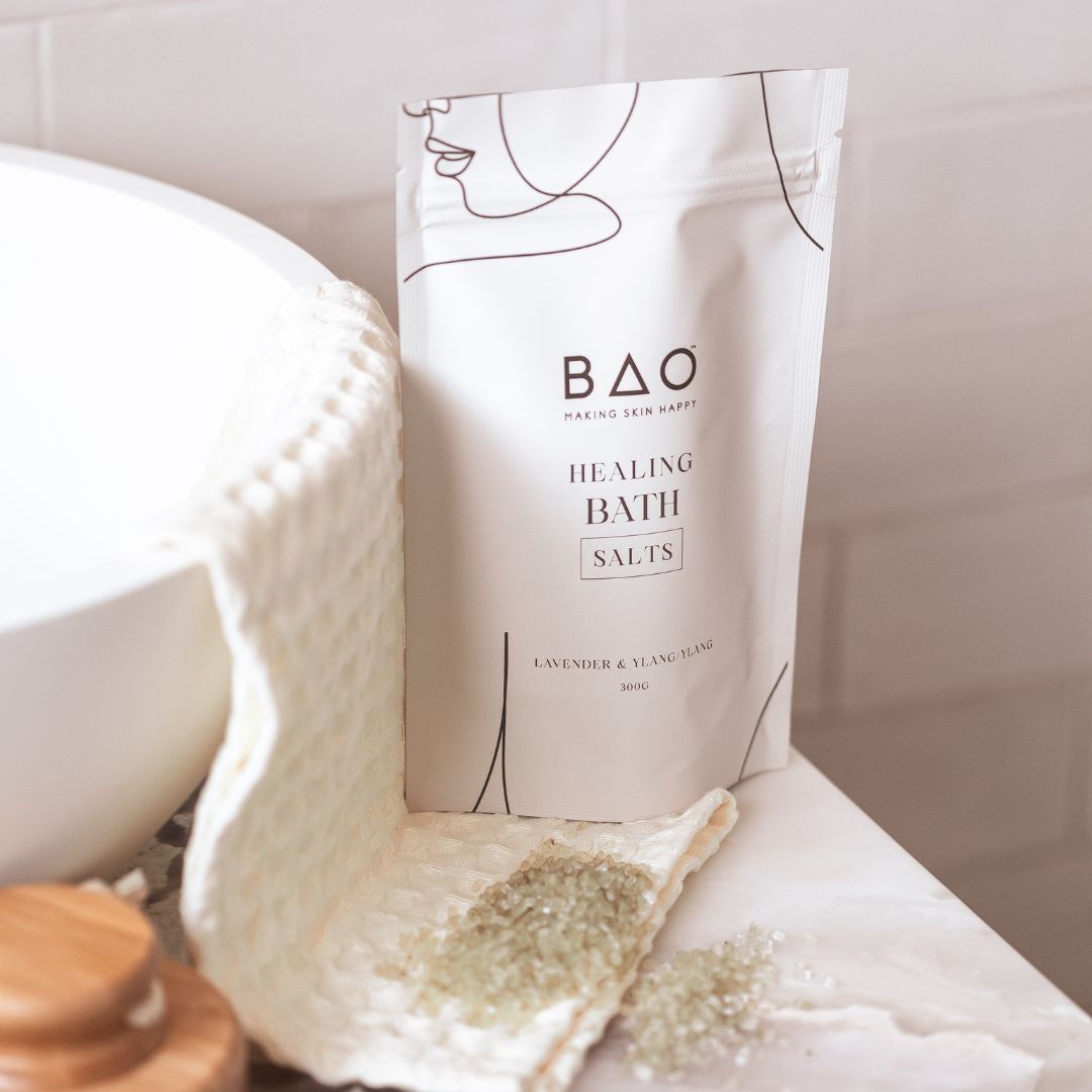 BAO Healing Bath Salts pouch beside a bowl and cloth with scattered bath salts