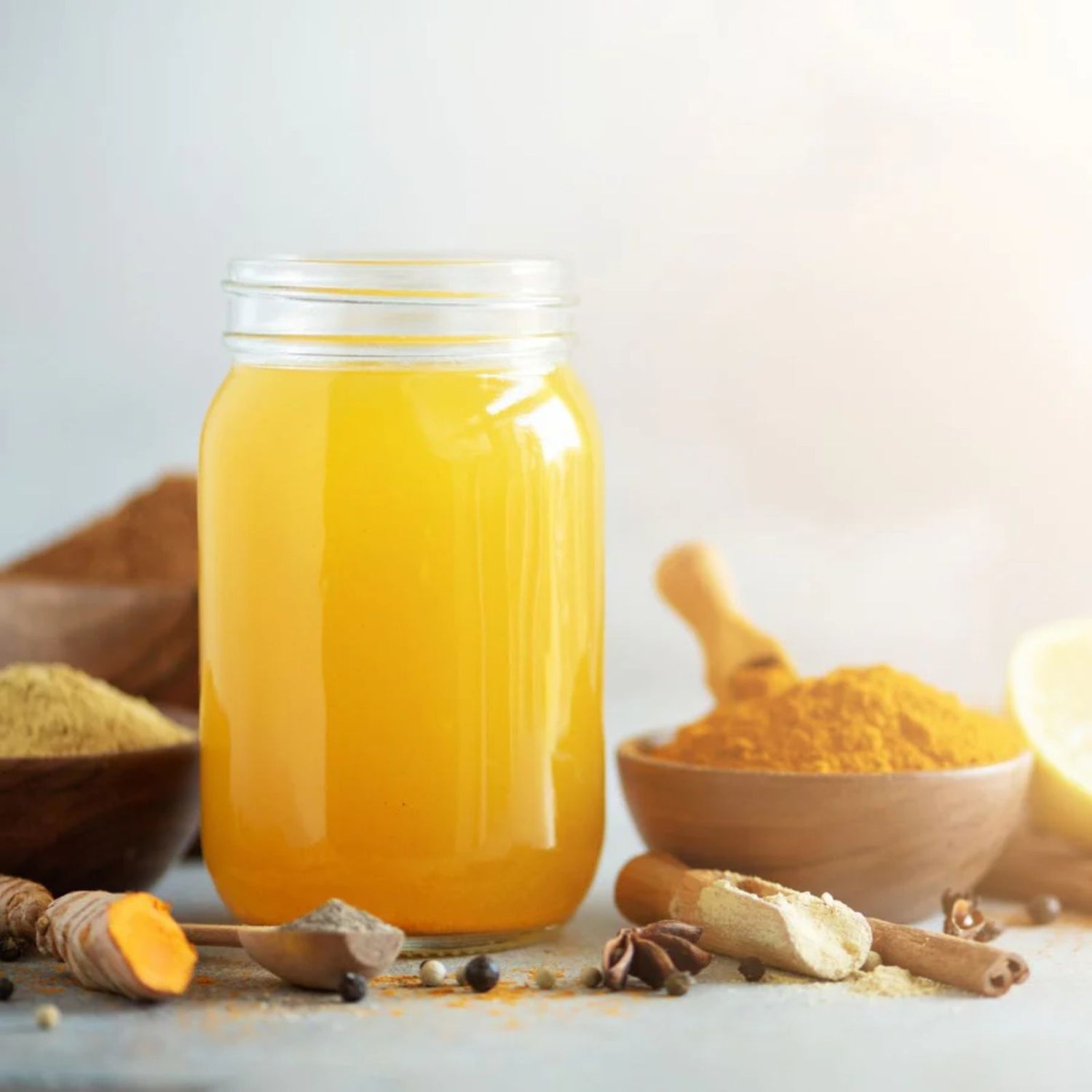 Glowing skin tonic in a recyclable glass with organic turmeric and ginger on a table.