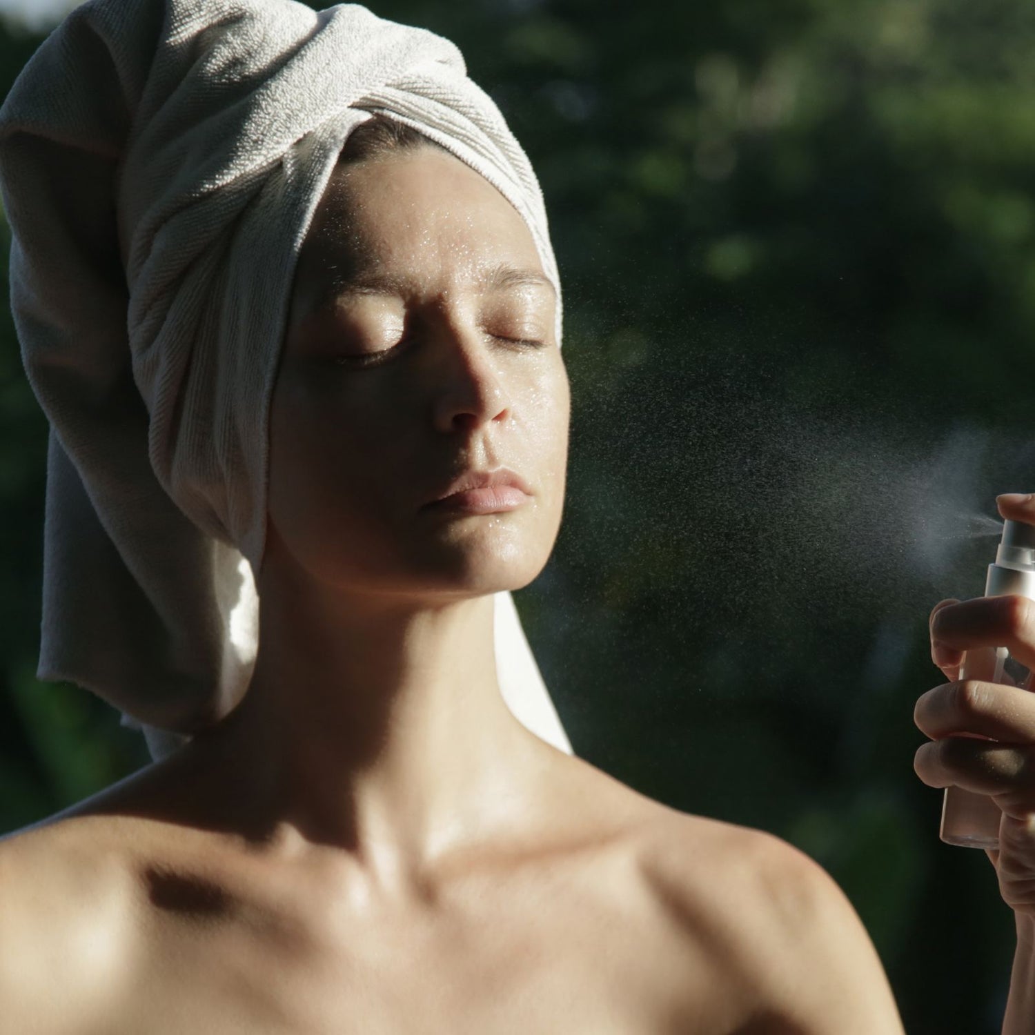 Woman spraying the Hydrating Rose Mist onto her face.