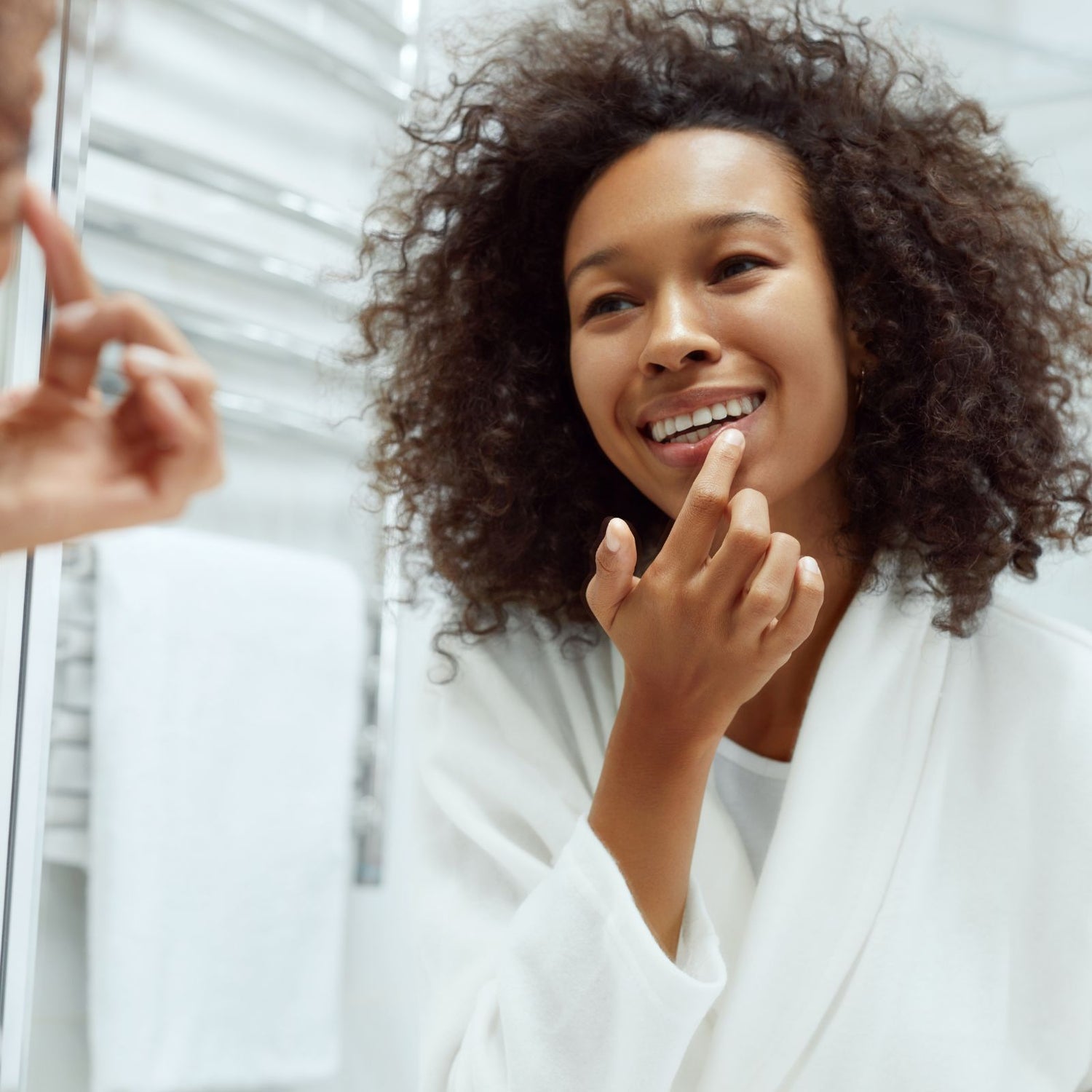Woman applying natural lip balm during morning skincare routine.