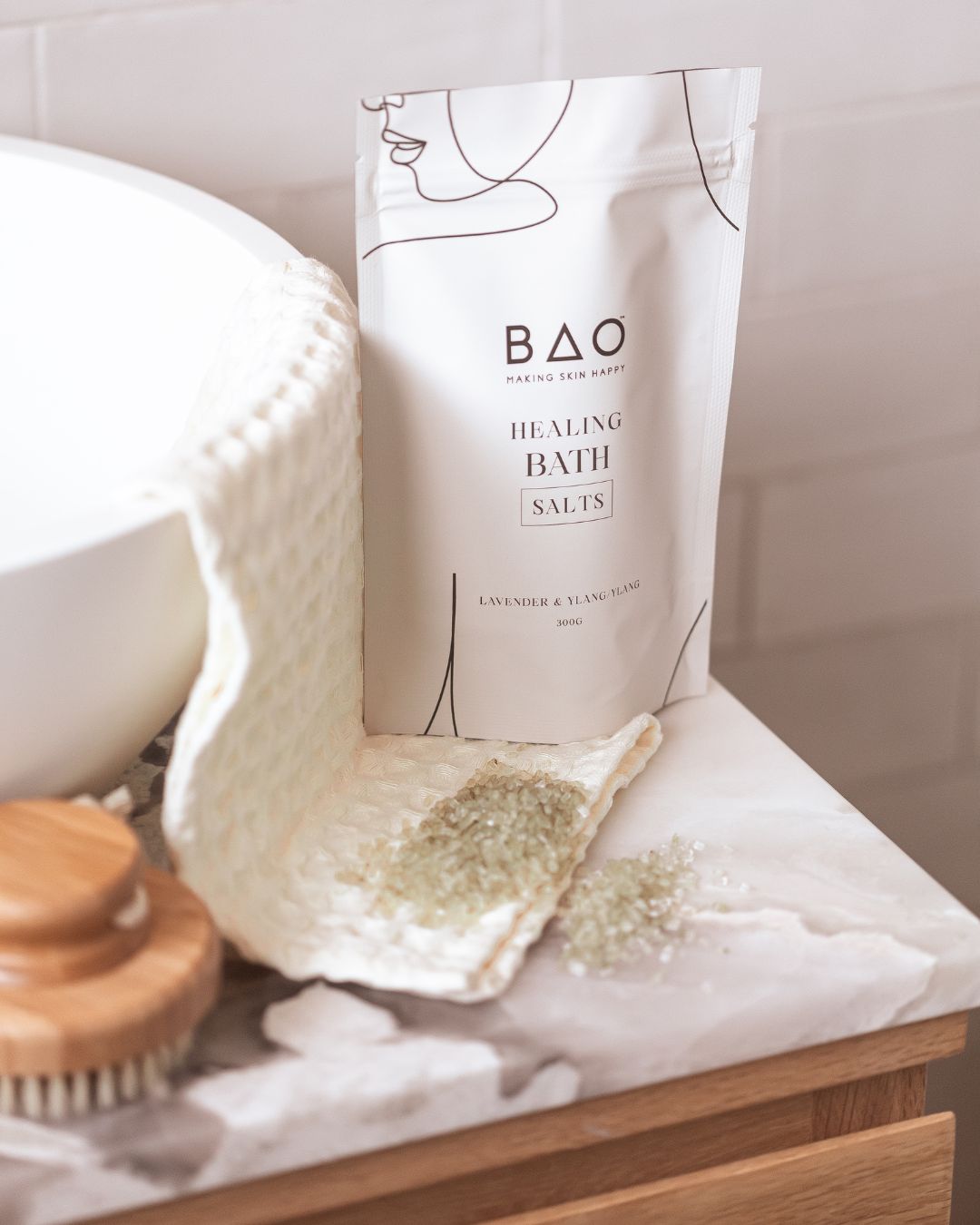 BAO Healing Bath Salts pouch on a marble counter with salt spilled onto a towel