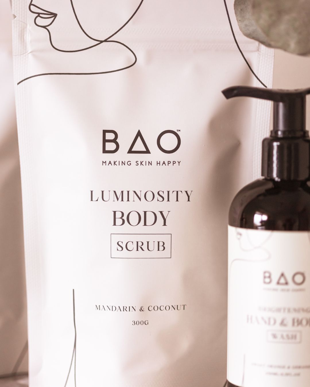 BAO Luminosity Body Scrub pouch held in an open palm in a shower