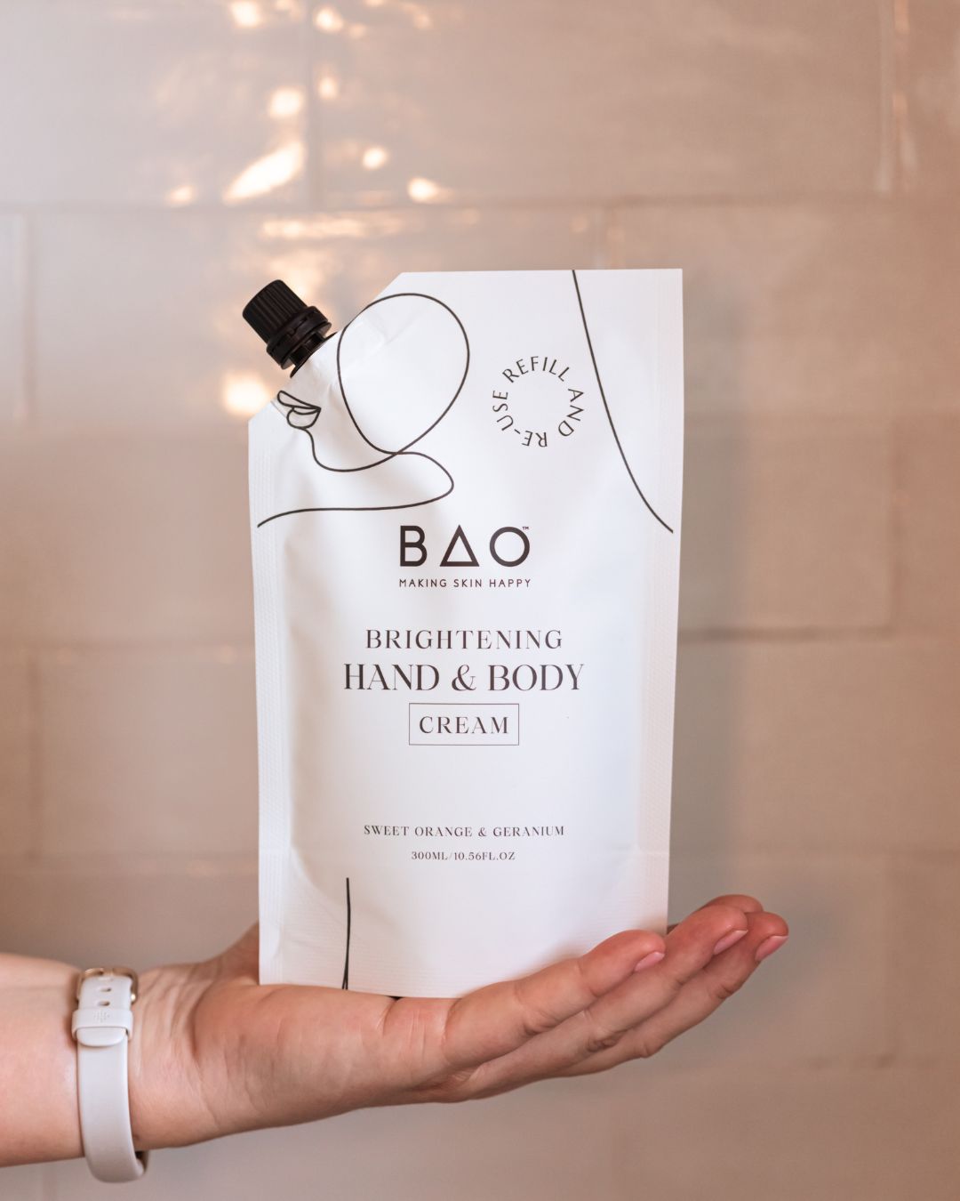 Hand holding BAO Brightening Hand &amp; Body Cream refill pouch