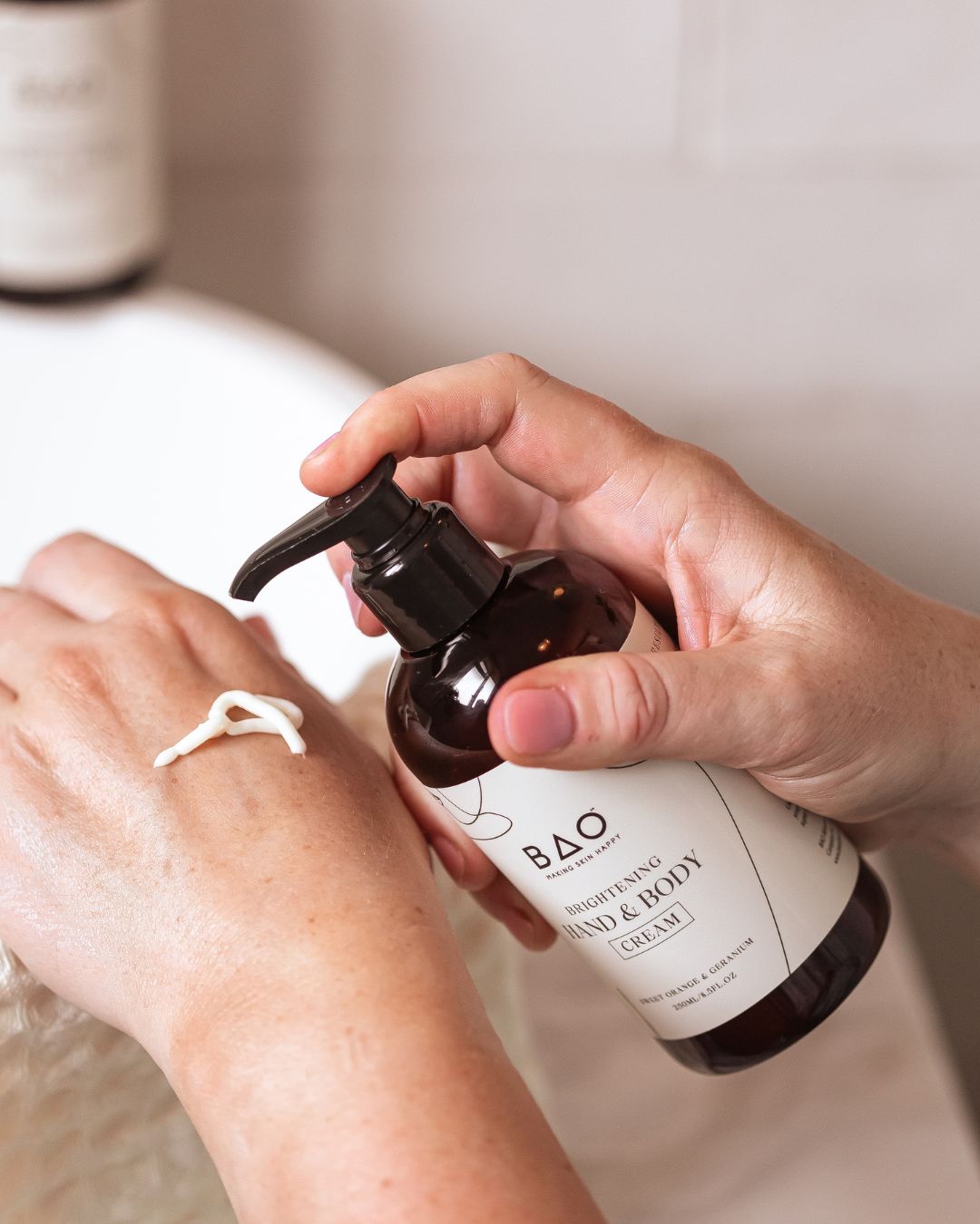 A bottle of BAO hand cream being placed on the back of a hand