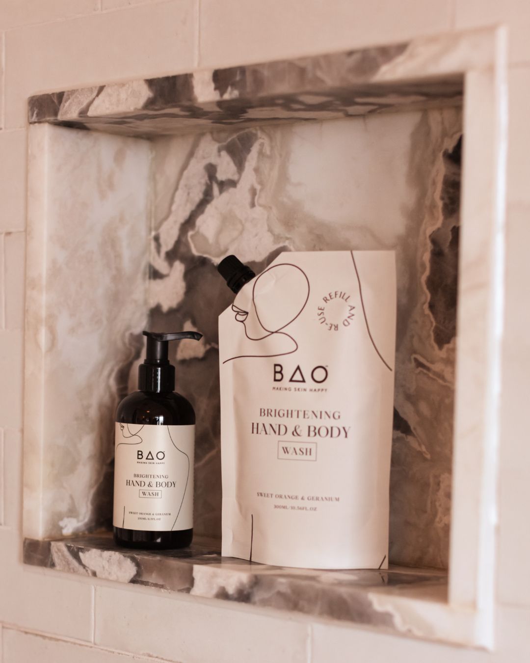 BAO Brightening Hand &amp; Body Wash bottle and refill pouch displayed in a marble shower niche